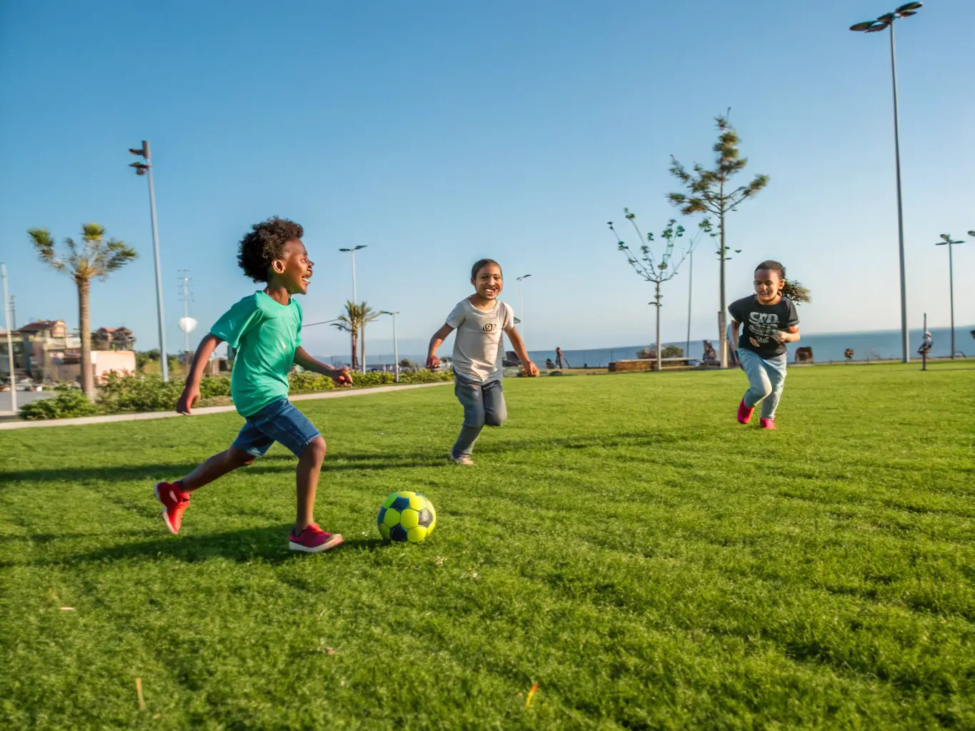 An image of children playing soccer in a park in Cheverny, with the Cheverny castle visible in the background.
